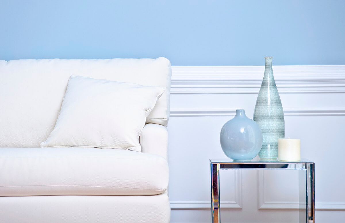 White painted Wainscoting panels on blue walll, behind couch and occasional table